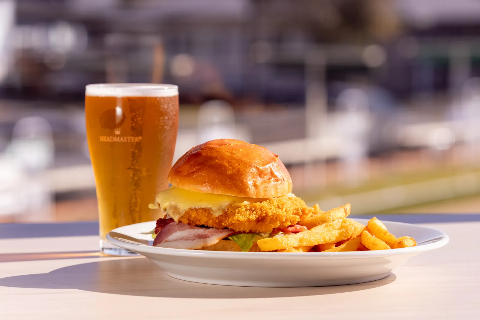 A chicken schnitzel burger with chips and a cold beer on the deck