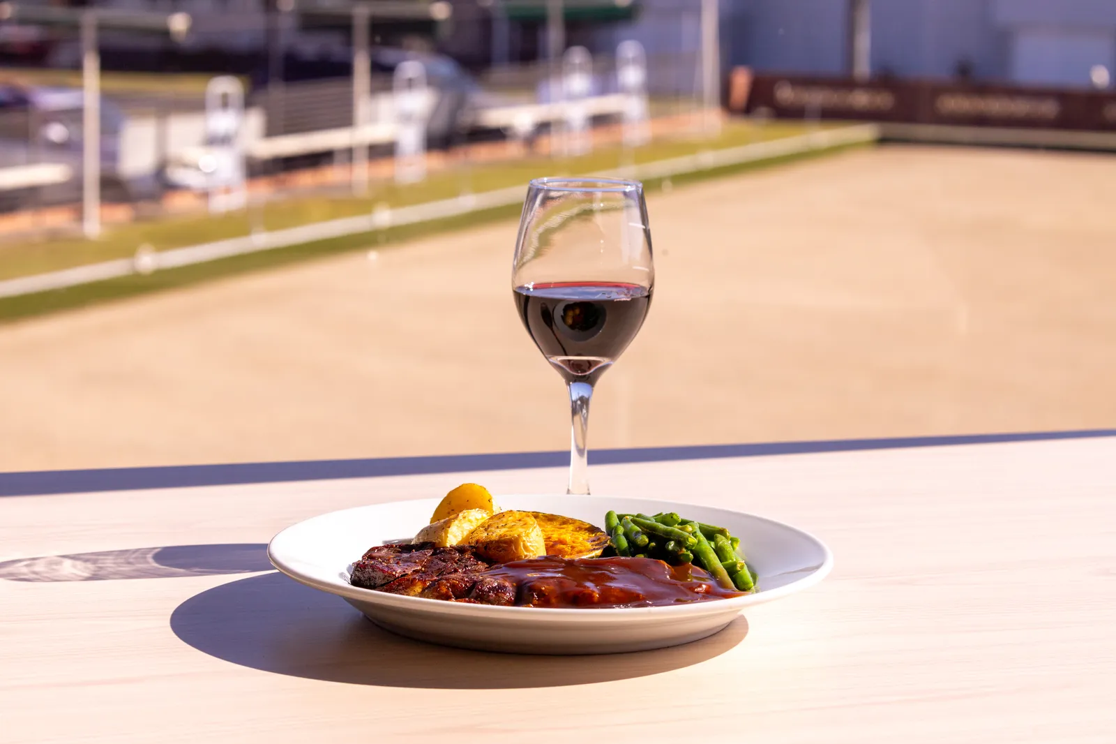 A steak dinner and a glass of red wine on the deck, looking out over the green