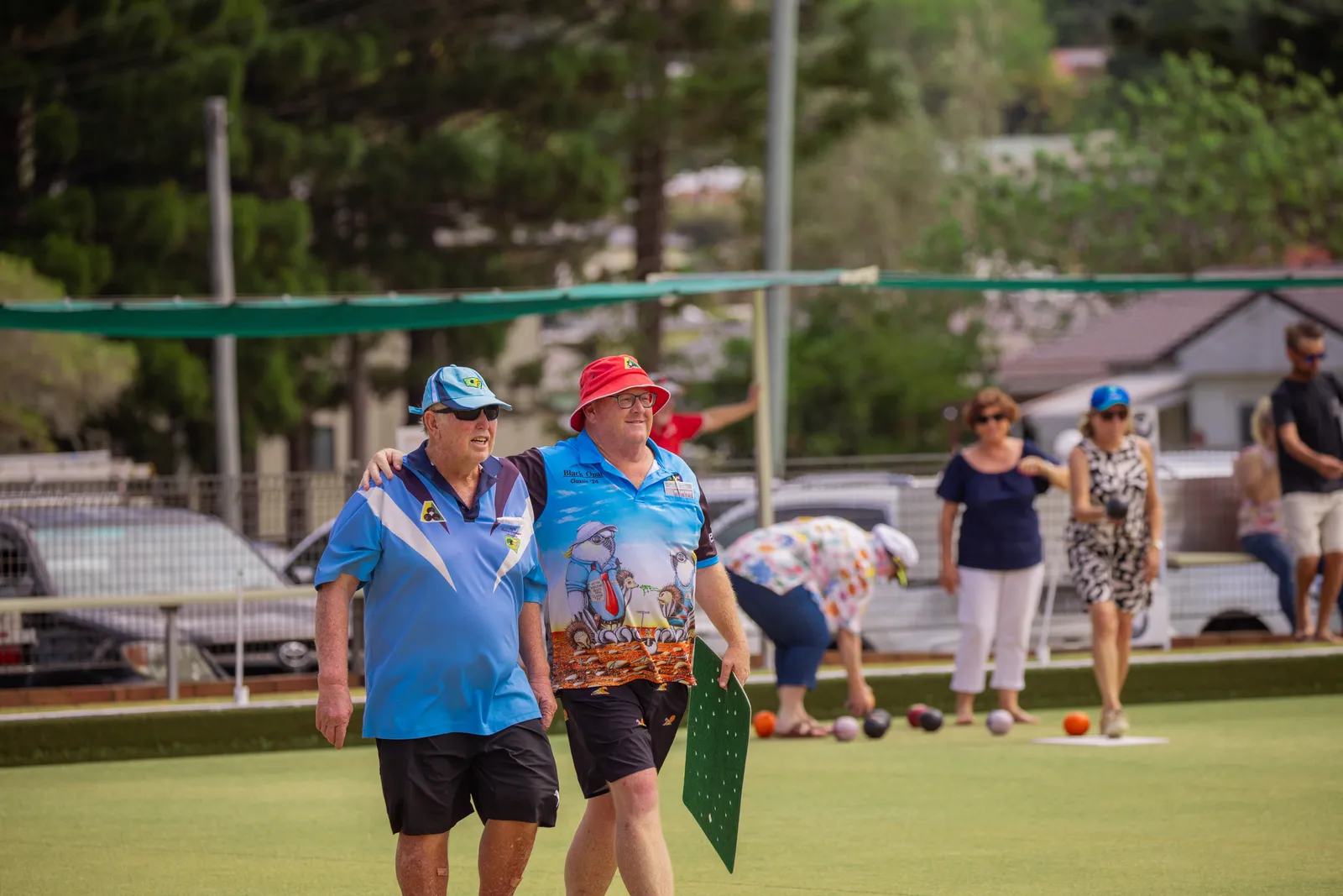 Two smiling members walking off the green after a game
